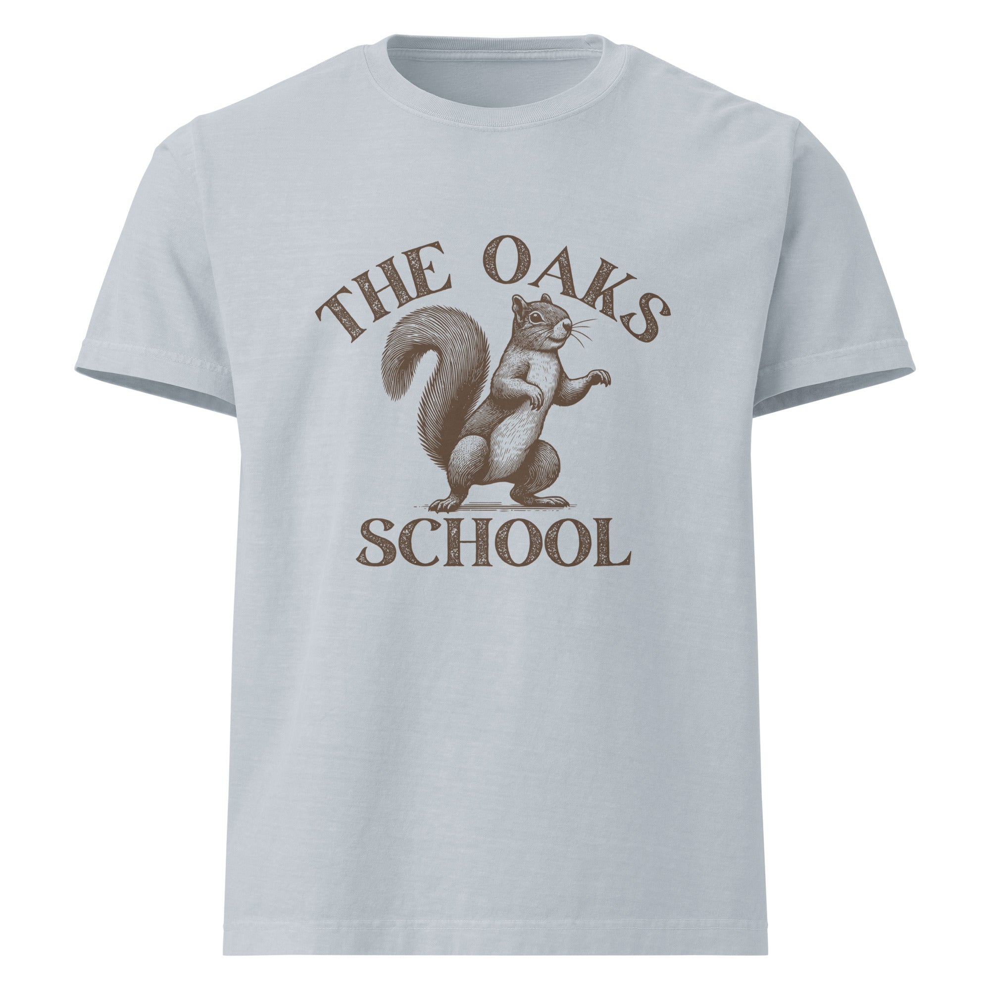 Product mockup: A washed denim colored tshirt on a white background featuring an illustration of a squirrel with text surrounding it that says "The Oaks School"