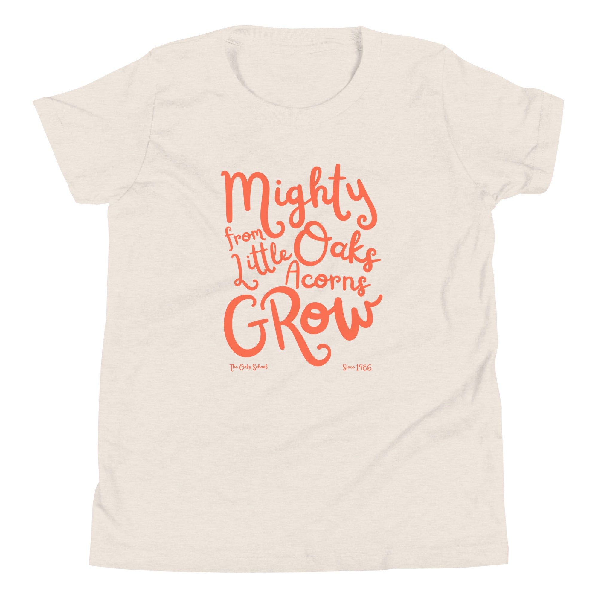 Product mockup: A heather dust colored tshirt on a white background with orange script text that says "Mighty Oaks from Little Acorns Grow" and "The Oaks School Since 1986"