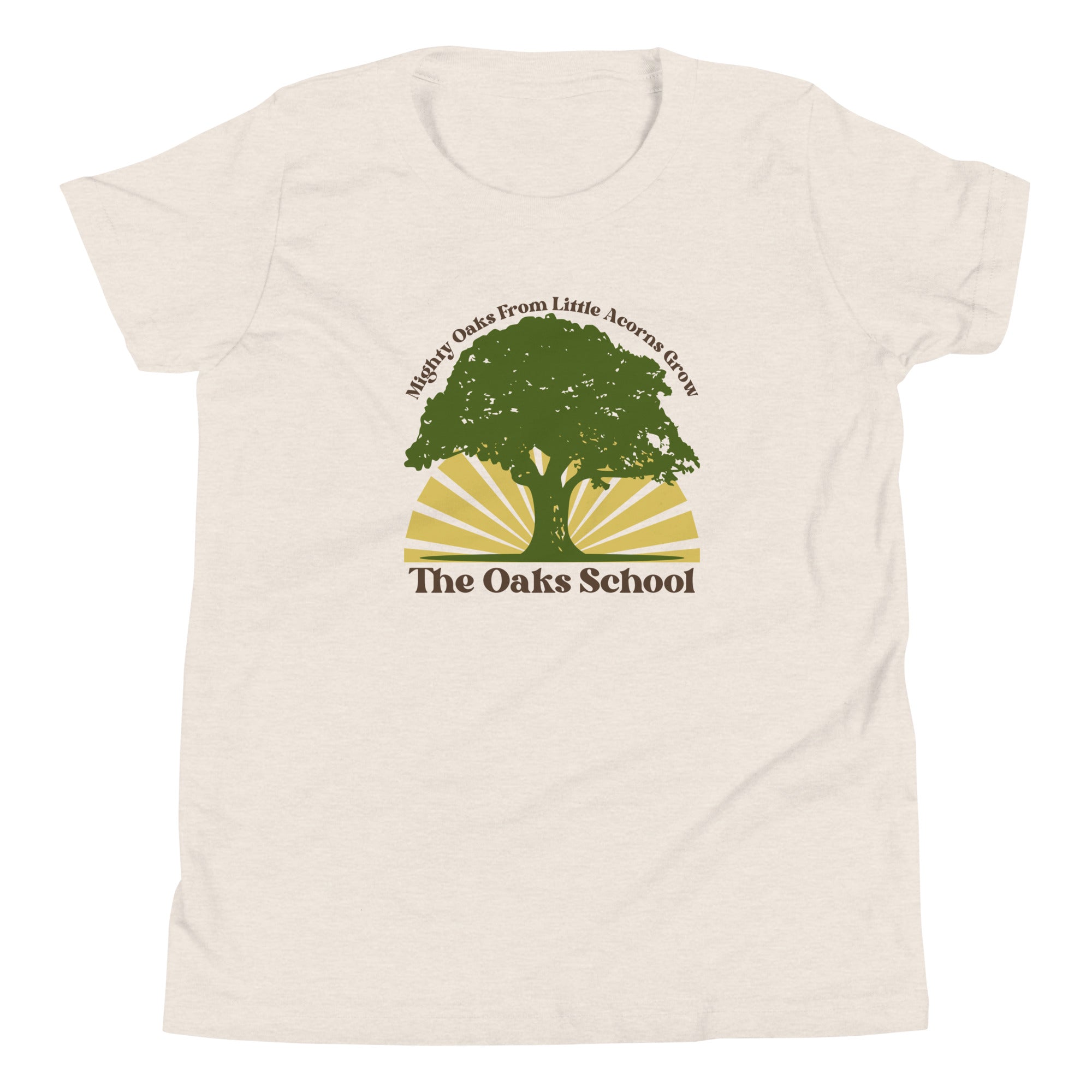 Product mockup: A heather dust colored tshirt on a white background featuring a green oak tree illustration on a yellow sunburst with text that says "Mighty Oaks from Little Acorns Grow" and "The Oaks School"