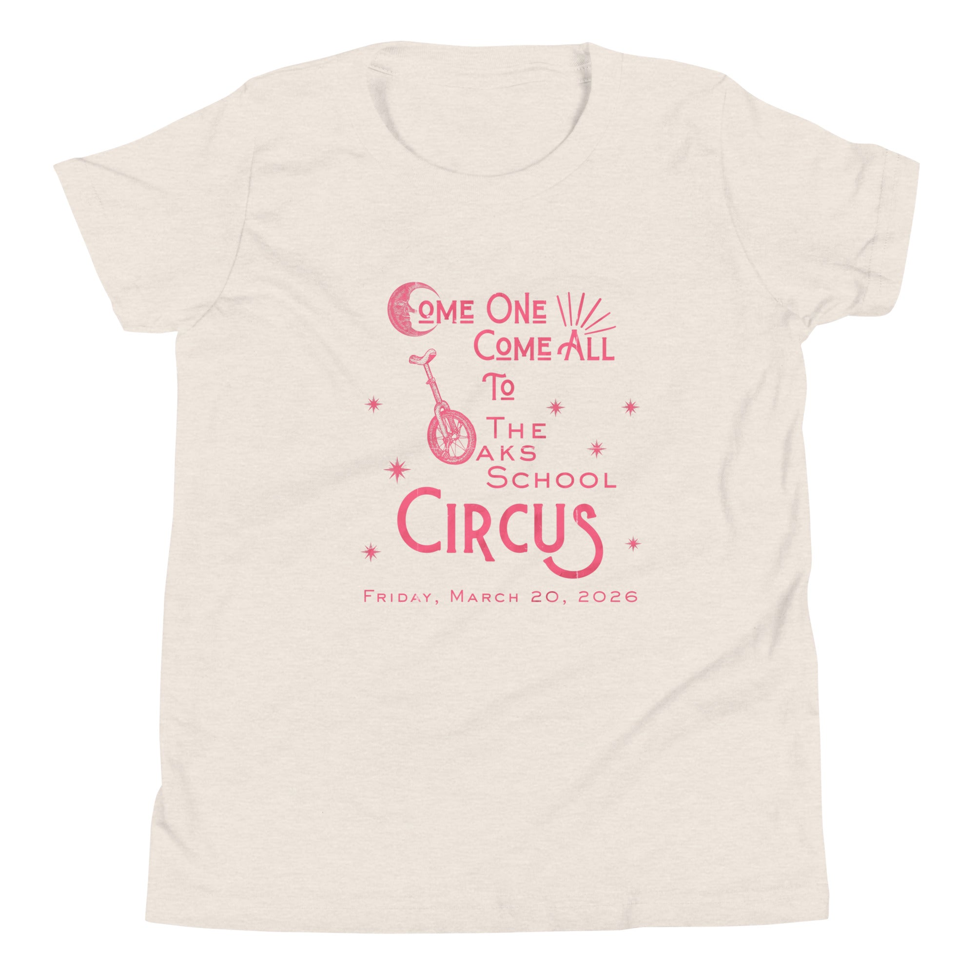 Product mockup: Heather dust colored tee with pink, weathered text "Come one, Call All to The Oaks School Circus, Friday, March 20, 2026." The "O" in "Oaks" is a unicycle wheel, the "C" in the first "Come" is a crescent moon, and there are stars sprinkled throughout.