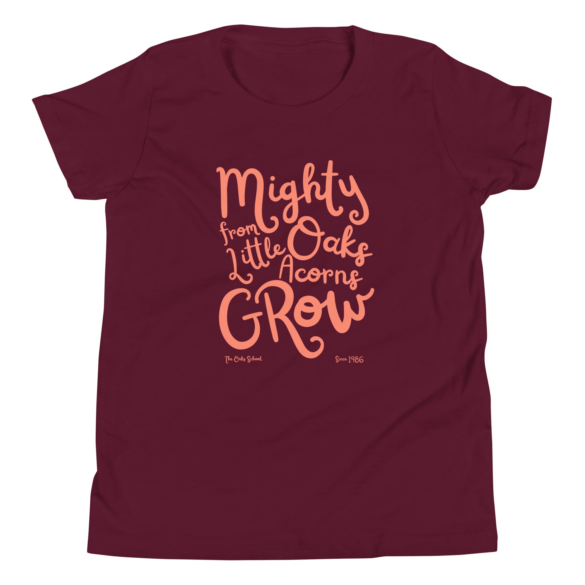 Product mockup: A maroon tshirt on a white background with orange script text that says "Mighty Oaks from Little Acorns Grow" and "The Oaks School Since 1986"