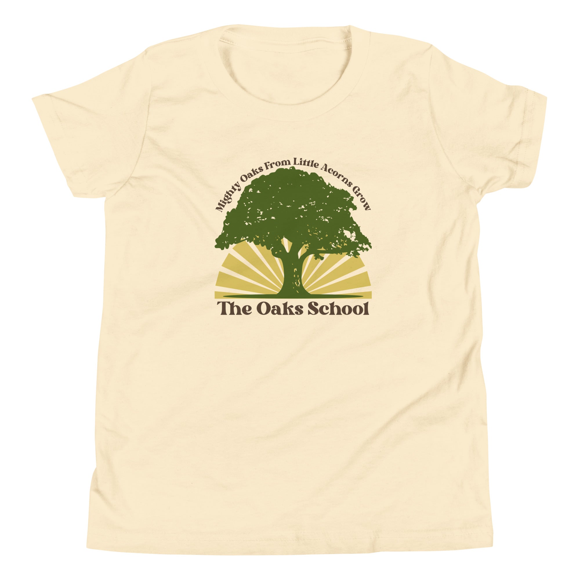 Product mockup: A natural colored tshirt on a white background featuring a green oak tree illustration on a yellow sunburst with text that says "Mighty Oaks from Little Acorns Grow" and "The Oaks School"