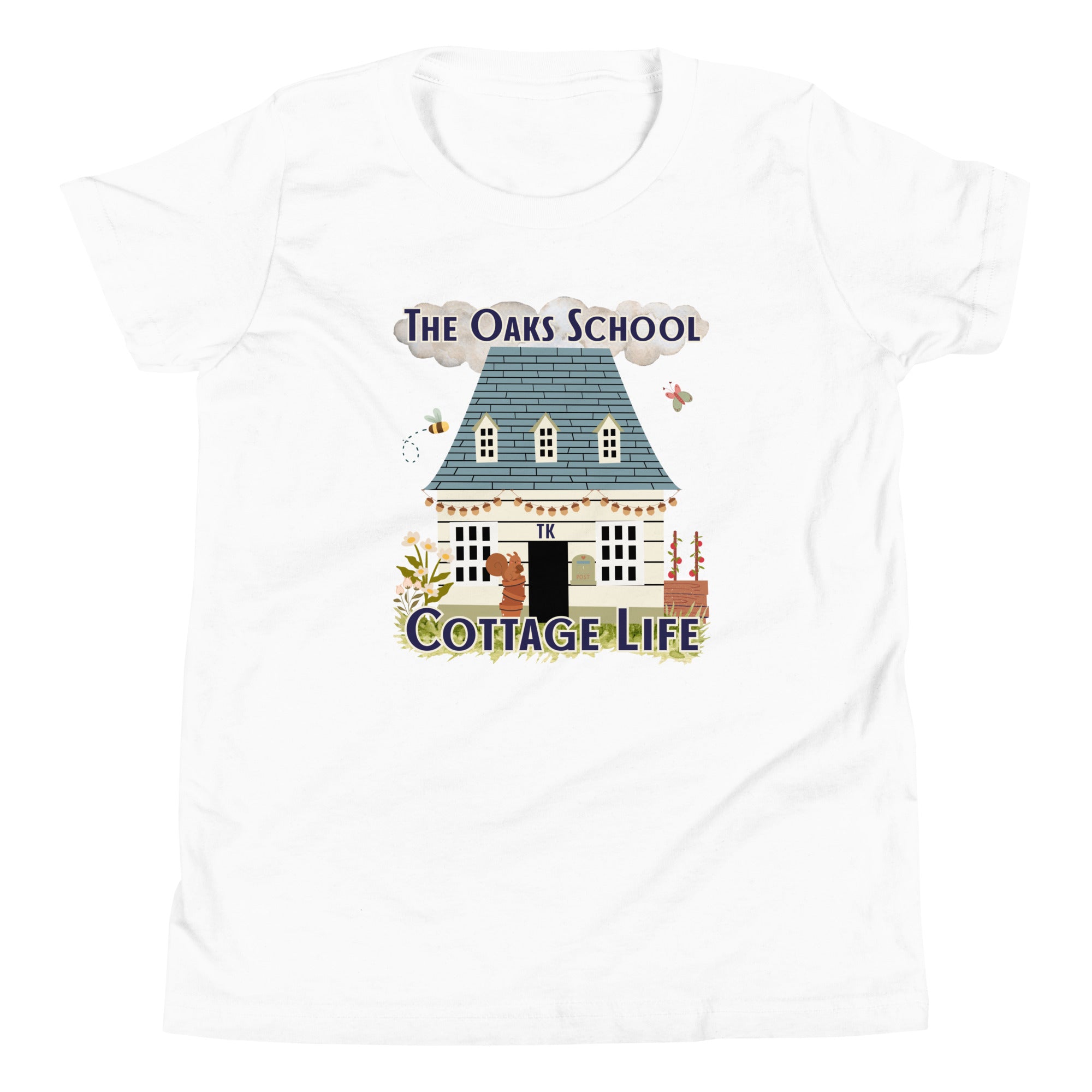 Product mockup: A white tshirt on a white background featuring an illustration of a white cottage and the text "The Oaks School" and "Cottage Life"